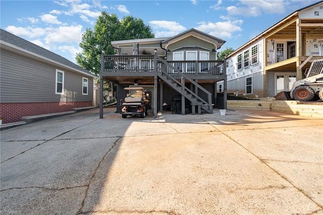 back of house with stairs, a wooden deck, driveway, and a carport