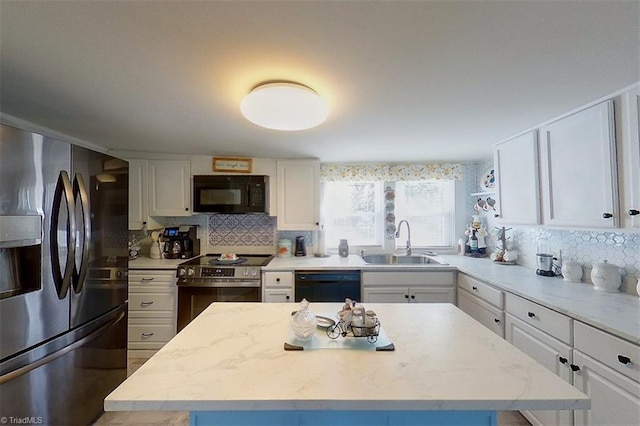 kitchen with sink, black appliances, tasteful backsplash, a center island, and white cabinets