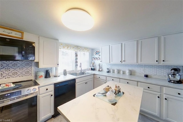 kitchen with black appliances, white cabinetry, sink, and a center island