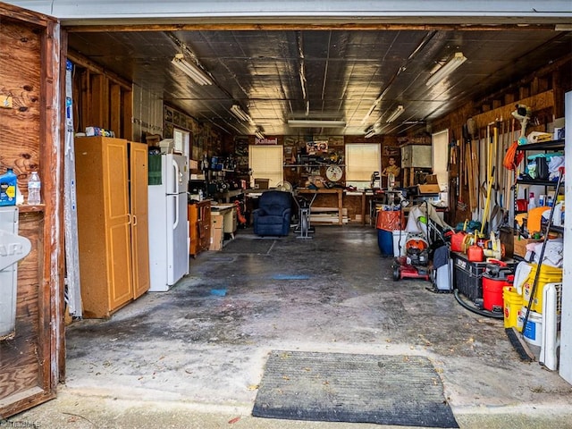 garage with wooden walls, a workshop area, and white fridge