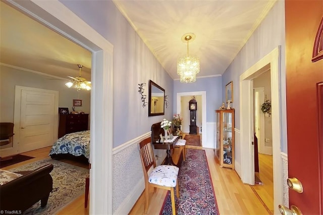 hall featuring light wood-type flooring, a chandelier, and crown molding