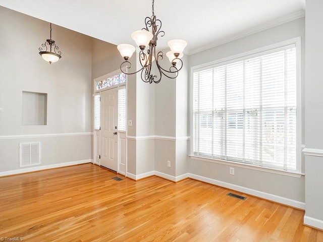 unfurnished room with crown molding, a chandelier, hardwood / wood-style floors, and a wealth of natural light