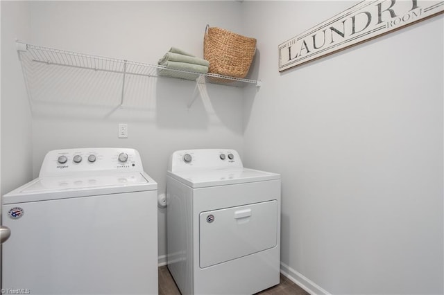 washroom featuring laundry area, washer and clothes dryer, baseboards, and dark wood-type flooring