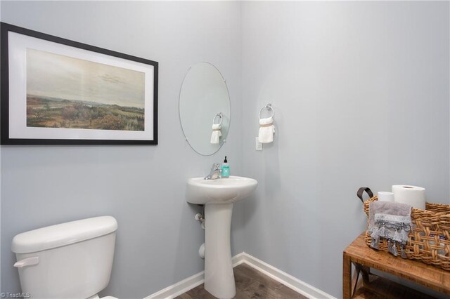 bathroom with baseboards, wood finished floors, and toilet