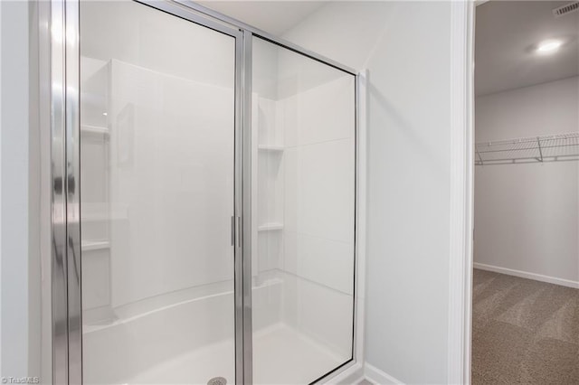 bathroom featuring visible vents, baseboards, a walk in closet, and a shower stall