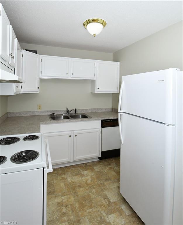 kitchen with a sink, white appliances, light countertops, and white cabinetry