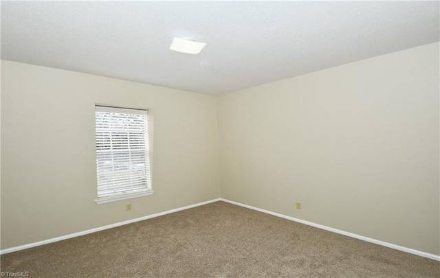 unfurnished room with carpet flooring and baseboards