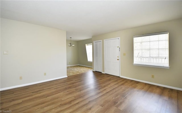 interior space featuring a notable chandelier, baseboards, and wood finished floors