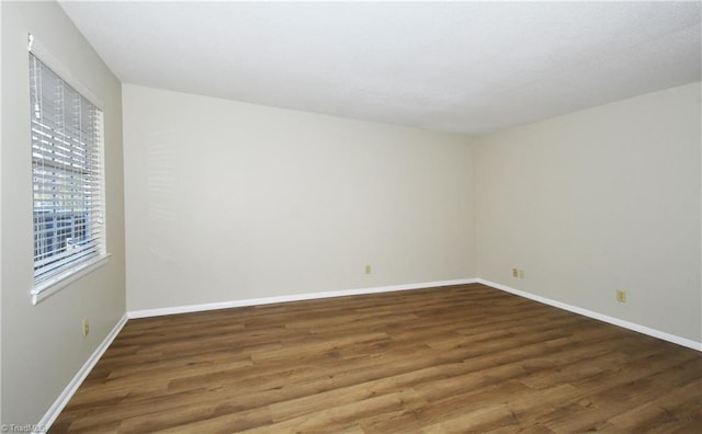 unfurnished room with baseboards and wood finished floors