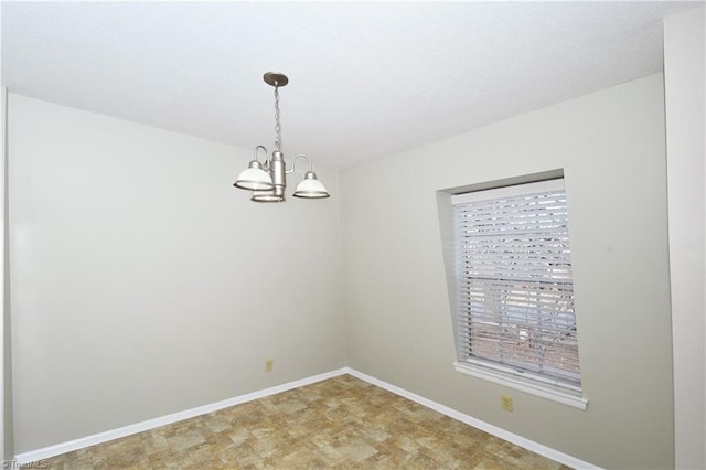 spare room featuring baseboards, plenty of natural light, and an inviting chandelier