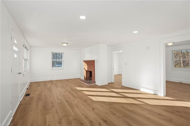 unfurnished living room featuring light hardwood / wood-style flooring and a brick fireplace