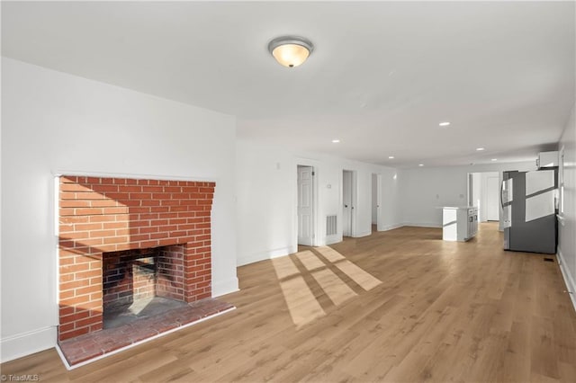 unfurnished living room with a brick fireplace and light wood-type flooring