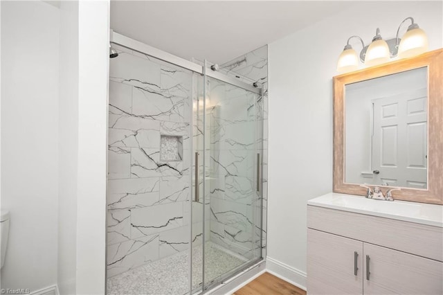 bathroom featuring toilet, vanity, a shower with shower door, and hardwood / wood-style flooring