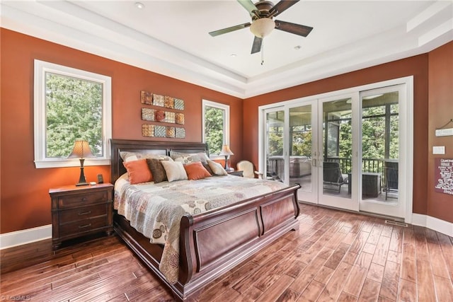 bedroom featuring ceiling fan, a tray ceiling, hardwood / wood-style flooring, and access to outside