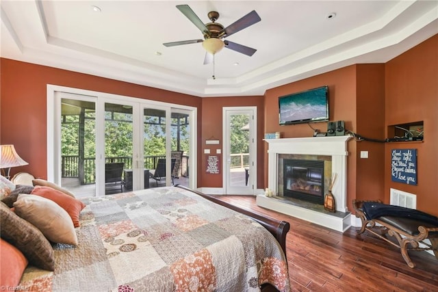 bedroom with access to outside, ceiling fan, a tray ceiling, french doors, and hardwood / wood-style flooring