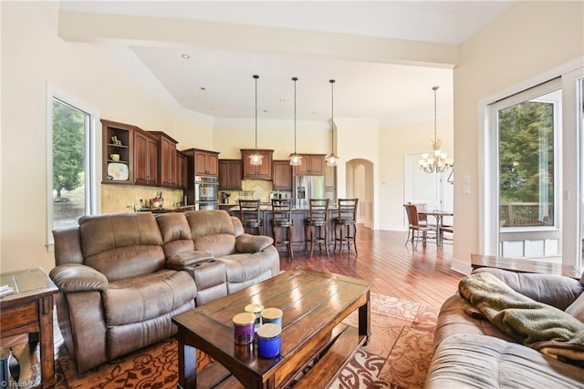 living room with dark wood-type flooring, vaulted ceiling, and a chandelier