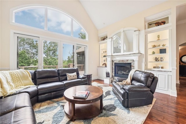 living room with a fireplace, built in features, high vaulted ceiling, and dark hardwood / wood-style floors