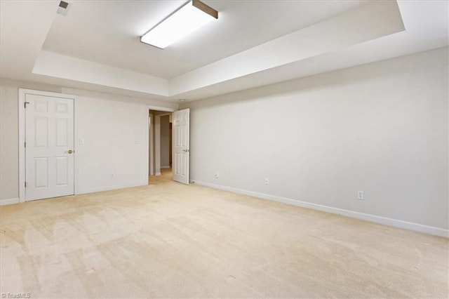 spare room with a raised ceiling and light carpet