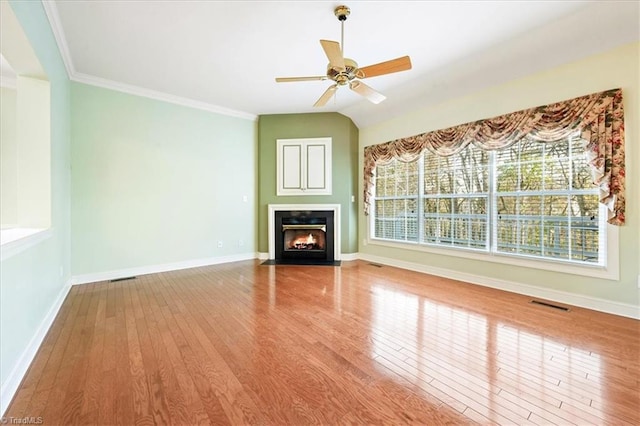 unfurnished living room with wood-type flooring, vaulted ceiling, ceiling fan, and ornamental molding