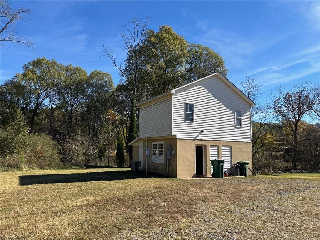 exterior space with central AC unit and a lawn