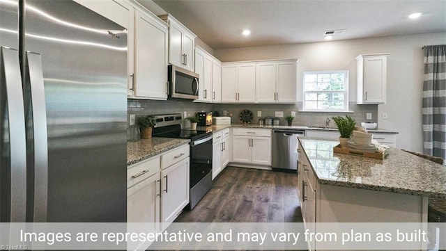 kitchen featuring white cabinets, appliances with stainless steel finishes, dark hardwood / wood-style flooring, and light stone counters