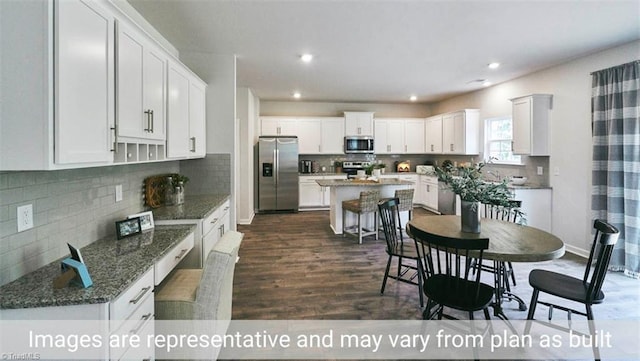 kitchen with white cabinets, dark hardwood / wood-style floors, a kitchen island, and stainless steel appliances