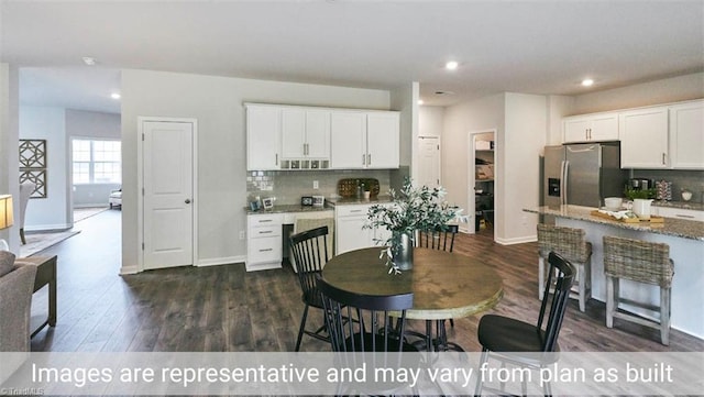 kitchen featuring decorative backsplash, stainless steel fridge, light stone counters, white cabinets, and dark hardwood / wood-style floors