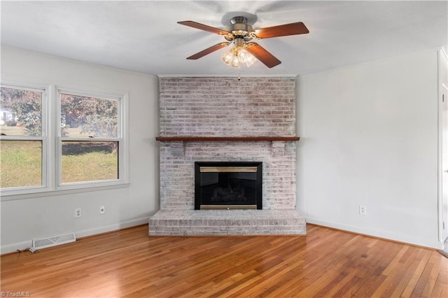 unfurnished living room featuring crown molding, hardwood / wood-style floors, ceiling fan, and a brick fireplace