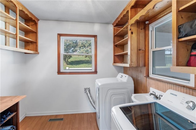 laundry area with sink, separate washer and dryer, and light wood-type flooring