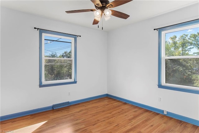 empty room featuring hardwood / wood-style floors, ceiling fan, and a wealth of natural light