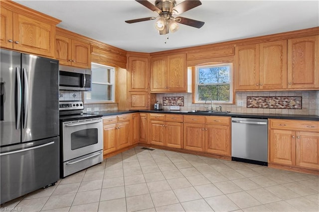 kitchen with sink, decorative backsplash, stainless steel appliances, and ceiling fan