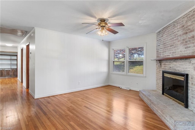 unfurnished living room featuring ornamental molding, a brick fireplace, light hardwood / wood-style floors, and ceiling fan