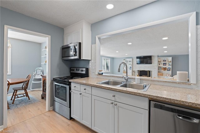 kitchen with a textured ceiling, white cabinetry, sink, and appliances with stainless steel finishes