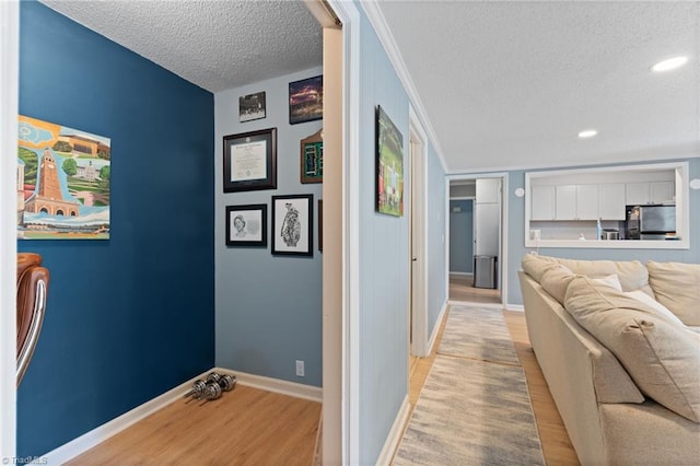 corridor with crown molding, light hardwood / wood-style flooring, and a textured ceiling