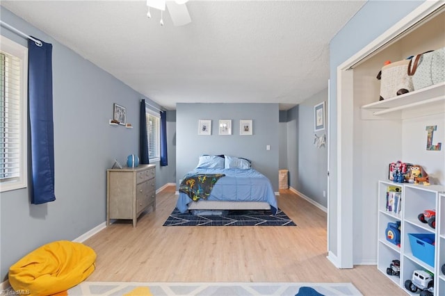 bedroom featuring ceiling fan, multiple windows, and light hardwood / wood-style flooring