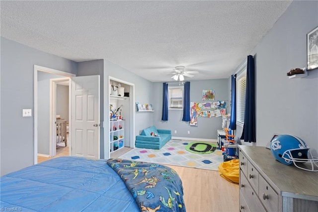 bedroom featuring ceiling fan, light hardwood / wood-style floors, and a textured ceiling