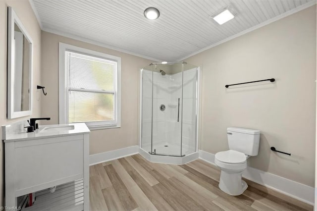 bathroom with toilet, wood finished floors, vanity, baseboards, and a shower stall