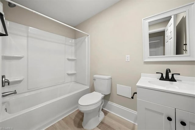 bathroom featuring toilet, washtub / shower combination, vanity, wood finished floors, and baseboards