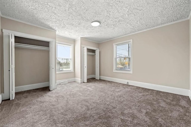 unfurnished bedroom featuring multiple closets, carpet, ornamental molding, and baseboards