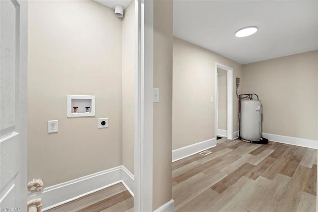 washroom with baseboards, wood finished floors, hookup for an electric dryer, water heater, and washer hookup