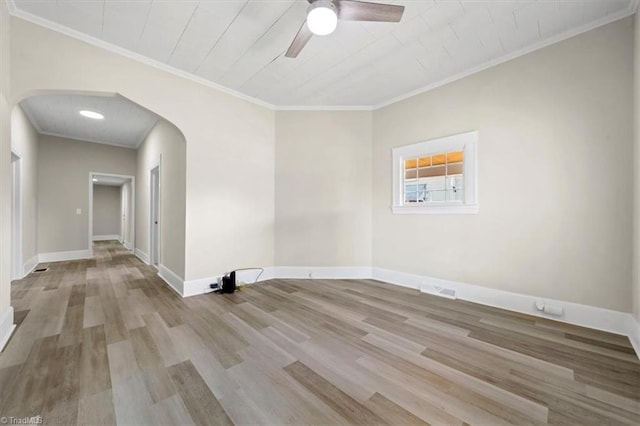 unfurnished room featuring arched walkways, wood finished floors, a ceiling fan, baseboards, and ornamental molding