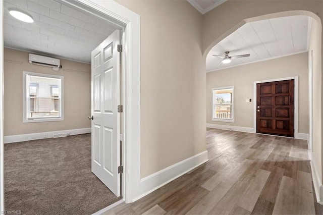 entryway with arched walkways, an AC wall unit, ceiling fan, and baseboards