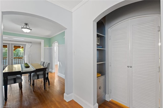 dining room featuring built in shelves, french doors, ornamental molding, and hardwood / wood-style flooring