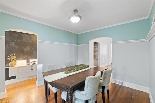 dining area with ornamental molding and hardwood / wood-style flooring