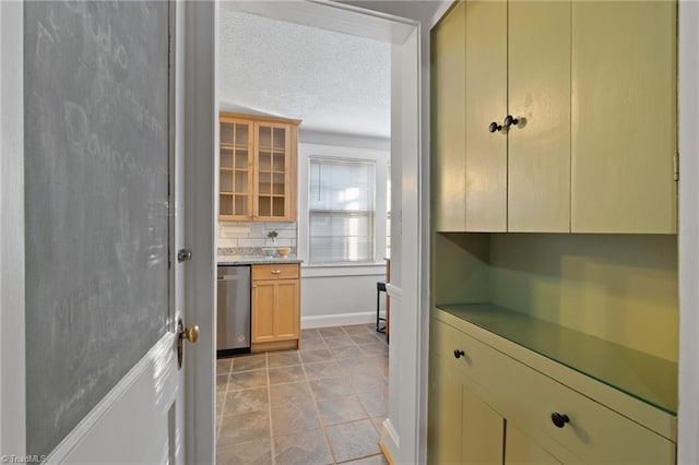 kitchen featuring decorative backsplash, a textured ceiling, and stainless steel dishwasher