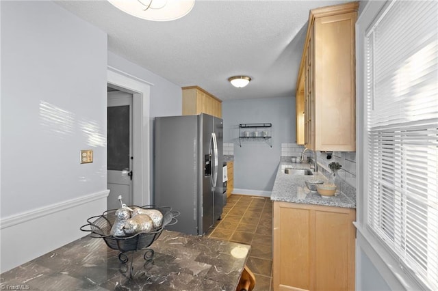 kitchen featuring light brown cabinets, sink, decorative backsplash, stainless steel fridge, and plenty of natural light