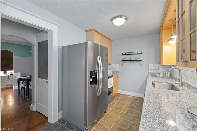 kitchen featuring decorative backsplash, stainless steel appliances, sink, light brown cabinets, and pendant lighting