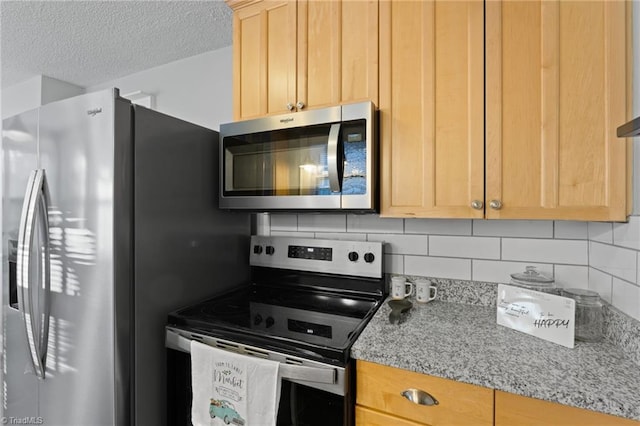 kitchen featuring decorative backsplash, light stone countertops, a textured ceiling, stainless steel appliances, and light brown cabinets