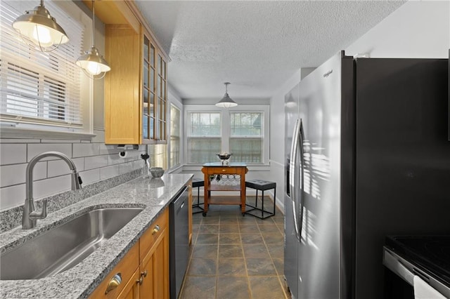 kitchen with pendant lighting, sink, light stone countertops, tasteful backsplash, and stainless steel appliances