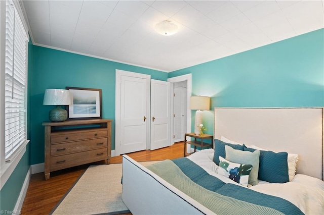 bedroom with multiple windows, crown molding, and hardwood / wood-style flooring